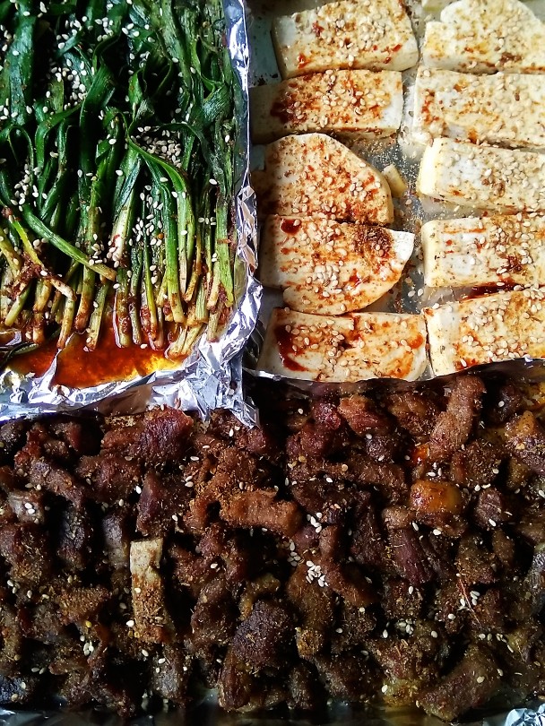 烤羊肉豆腐韭菜,拿出烤盘放入准备好的豆腐韭菜,撒上适量芝麻,再烤20分钟
