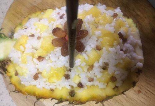 版纳香甜糯萝饭,再取几颗葡萄干做装饰,用筷子给菠萝饭插数个小孔以便上汽