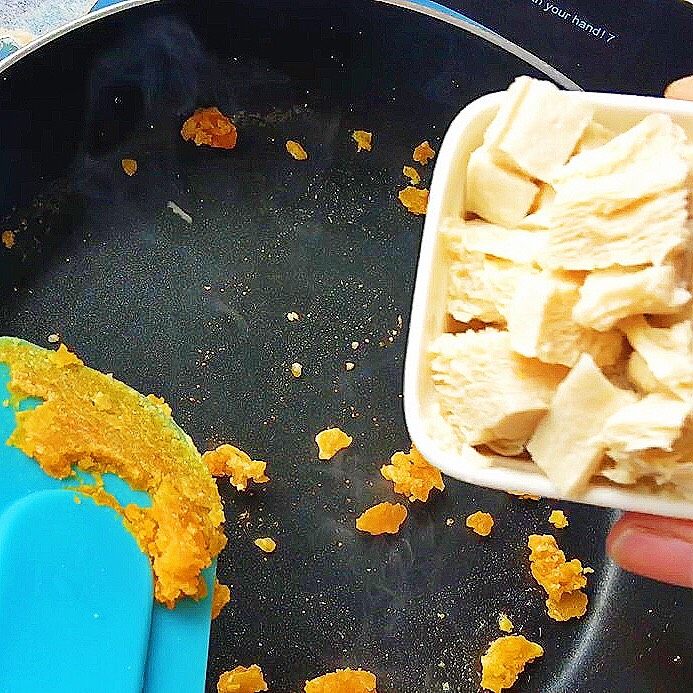 咸蛋黄焗冻豆腐,再倒入豆腐翻炒，倒入适量清水煮开