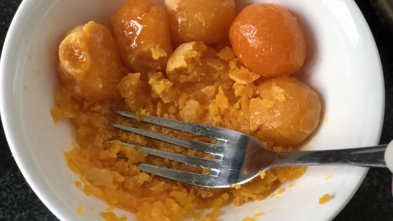 时令菜谱-网红艾草青团,新鲜咸鸭蛋磕出蛋黄,上锅蒸熟,用叉子压碎。