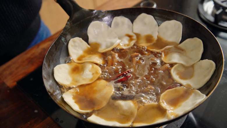 地锅鸡【曼食慢语】,将饼围着锅贴一圈,盖上锅盖,继续炖煮约15分钟。15分钟后开锅盖,加入炸过的蒜头,拌入鸡肉中,调整贴饼的位置,把它埋到汤里头