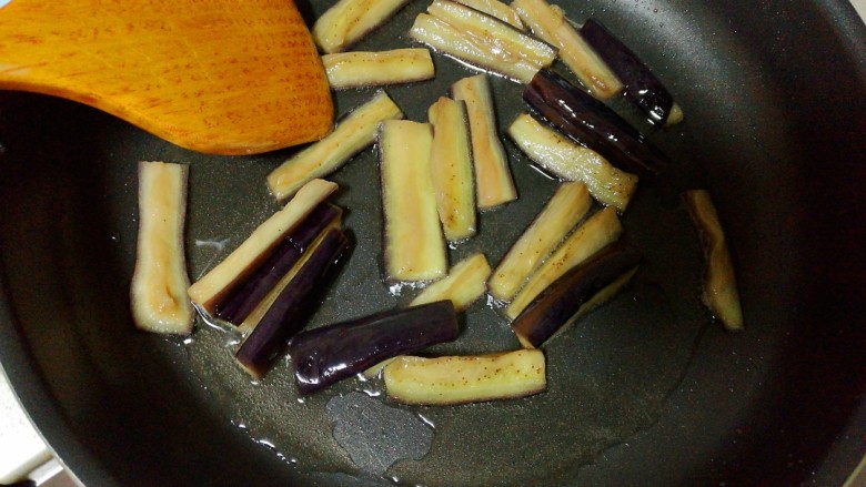 豆角烧茄子,锅中放油烧热,放入腌好的茄条,煸至茄子变色变软后盛出。