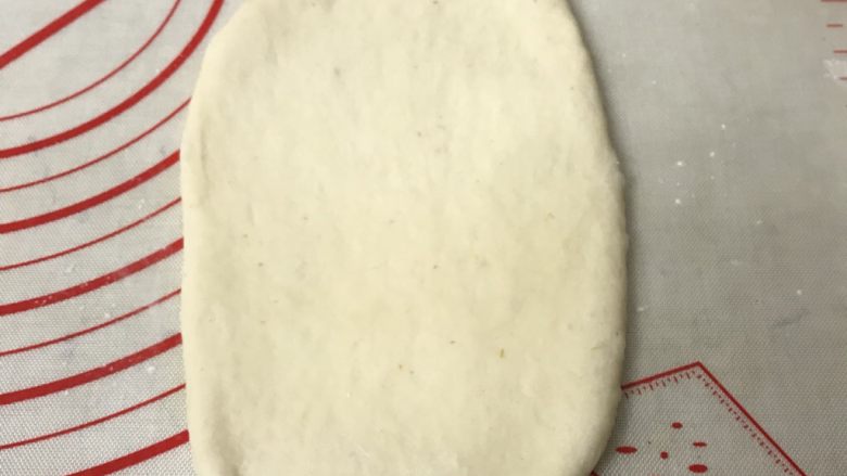 奶香葡萄干吐司
,取一个松弛好的面团用擀面杖从中间向两头擀成长舌形,边上的气泡用手拍打掉