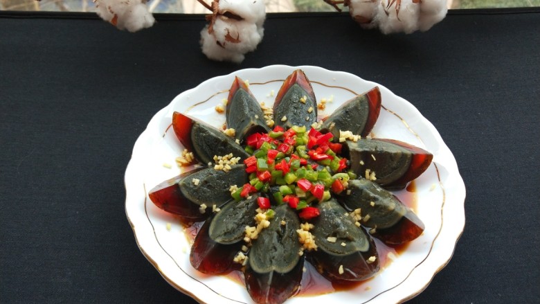 浇汁黑色松花蛋,辣椒丁放入松花蛋中间,撒上调好的汁即可食用。