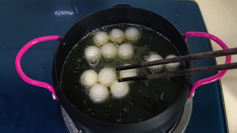 干菜炒汤圆,把汤圆用筷子挨个放入,并用筷子不断翻拌,以防粘连