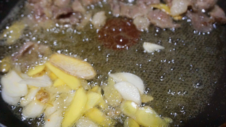 家常白油肉片,肉片受热滑散后,将肉片推到锅边,再下姜片、蒜片爆香锅
