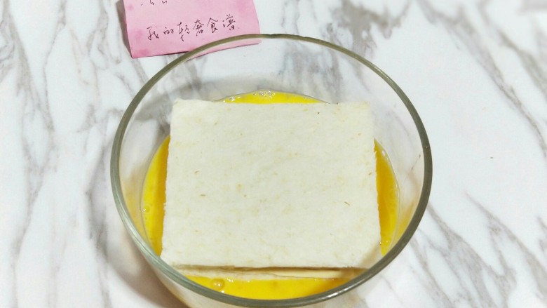 #辅食计划#芝士培根三明治,之后把夹好培根和芝士的吐司放在蛋液中,两面全部沾满蛋液。