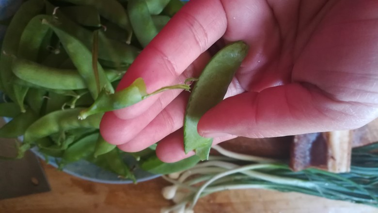 #下酒菜#绿油油的腊肉炒豌豆荚,看,揪下头子上的那个开花的地方,左一下,右一下,就把丝给弄干净了。