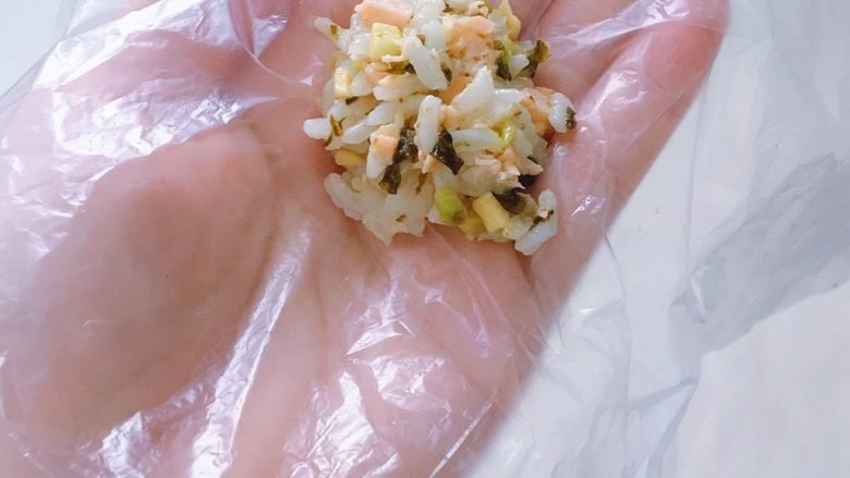 海苔牛油果三文鱼饭团,拿一张保鲜膜或者保鲜袋,取一勺放在保鲜膜上