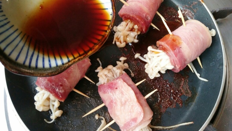 金针菇培根卷,待培根每个面都煎熟后,倒入调好的料汁。