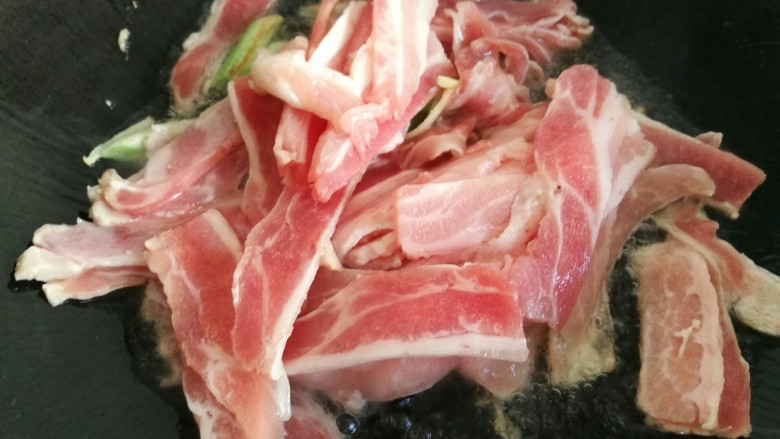 酱香蒜苔炒肉,炒锅放油,放入葱姜和五花肉片煸炒。