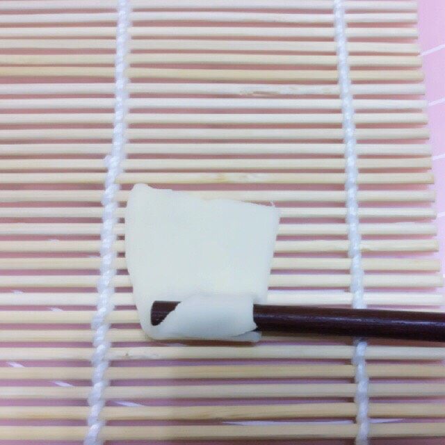 自制空心面(饺子皮版),取一片放在寿司帘上,用筷子压住角向上卷,
