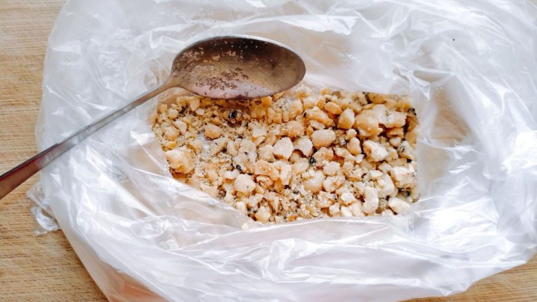 卡布奇诺牛奶布丁,花生糖剥掉糖纸之后,放到准备好的保鲜袋里,用勺背将其压碎。