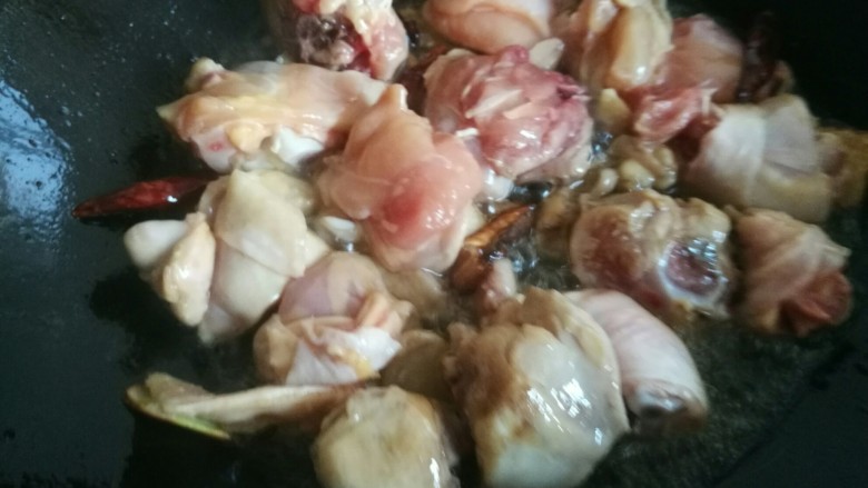 家常黄焖鸡,糖色炒好后放入腌制好的鸡块,煸炒至鸡肉表面变色。