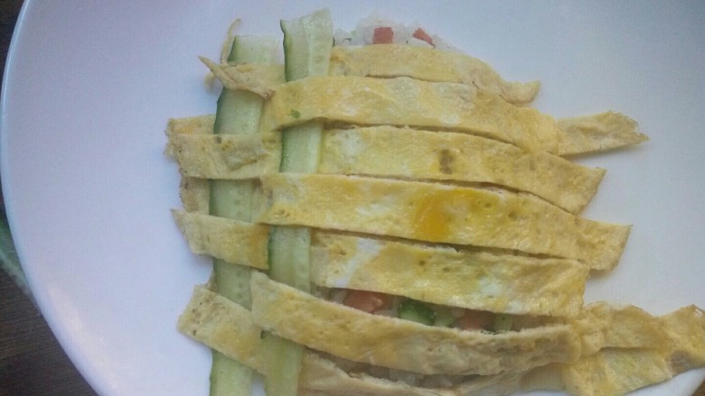 创意菠萝饭,像编花篮一样把黄瓜皮条编进去,编好后将侧面多余的剪掉。