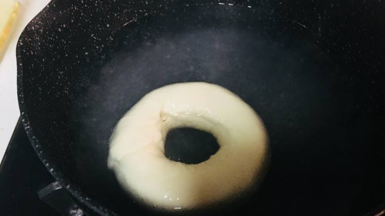 原味贝果,取一个锅,放入水和糖。煮沸。小火保持温度,但不要冒大泡泡。将面圈放入锅中,每面30到40秒。取出沥干多余水分。