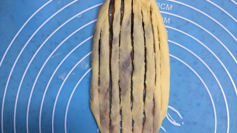 扭扭层层豆沙面包,用擀面杖轻轻的擀成薄薄的椭圆形,再用切刀划口,除两头不划断中间刀口划断