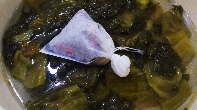 酸辣巴沙鱼,把酸菜放进锅里,加适量的水,放入装了白芷的花椒和尖辣椒袋子,大火烧开,小火闷十分钟左右