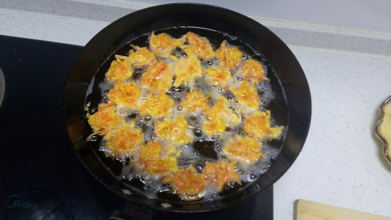 胡萝卜丸子,锅中放入适量油,五层热,用勺子挖一勺,放入手上用勺子团圆,再放入锅中。