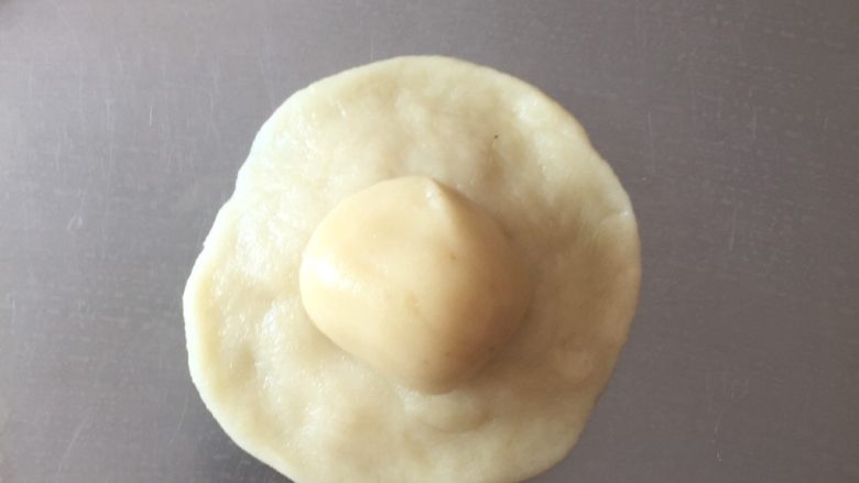 老婆饼(糯米椰蓉馅)零失败,拿一块分好的水油皮面团,擀成同包子皮一样,再把油酥面团放中间,同包包子一样的手法包好,剂子口朝下!