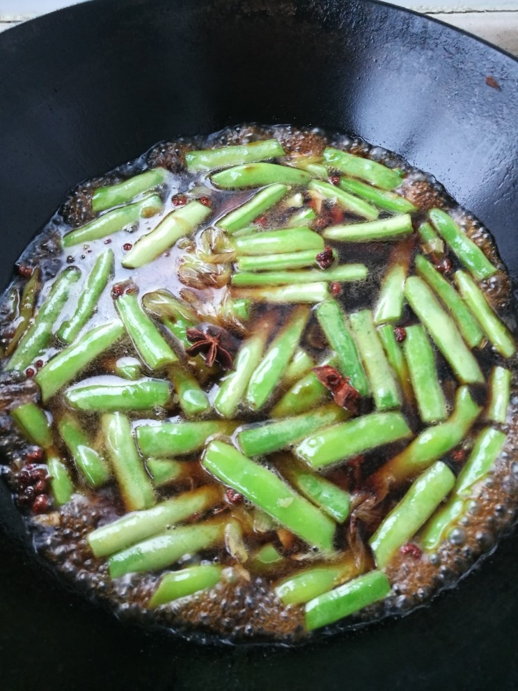 豆角焖面,倒入<a style='color:red;display:inline-block;' href='/shicai/ 788'>生抽</a><a style='color:red;display:inline-block;' href='/shicai/ 762'>老抽</a>和盐翻炒均匀。然后加入水淹过豆角。放入两粒<a style='color:red;display:inline-block;' href='/shicai/ 695'>八角</a>。