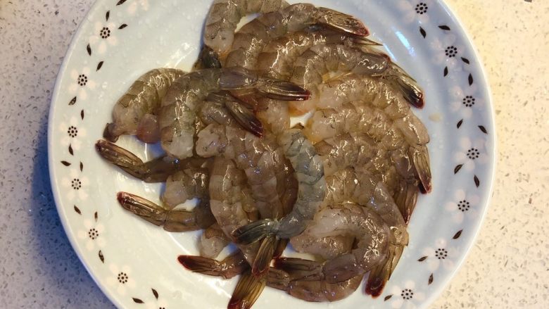 虾扯蛋,把冰箱里取出的冻虾冲软后,剥壳去虾线,只留下尾部的壳。
