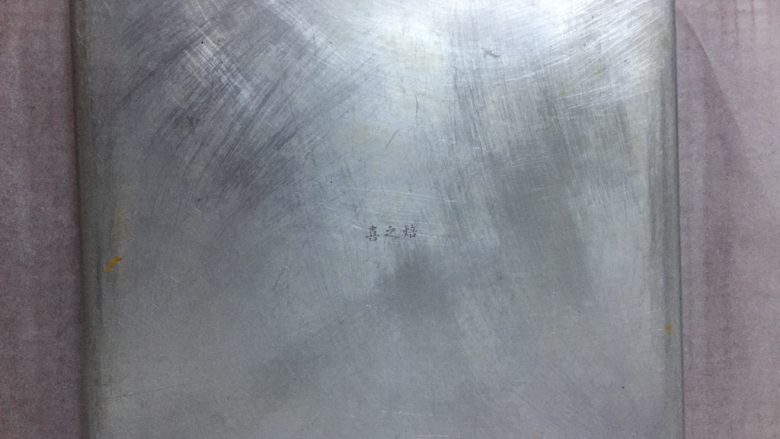 辣肉松面包卷,取一个大于烤盘的晾网,铺上一张大于烤盘的烘焙纸,将烤盘倒扣在烘焙纸上,晾预2分钟,不烫手即可。