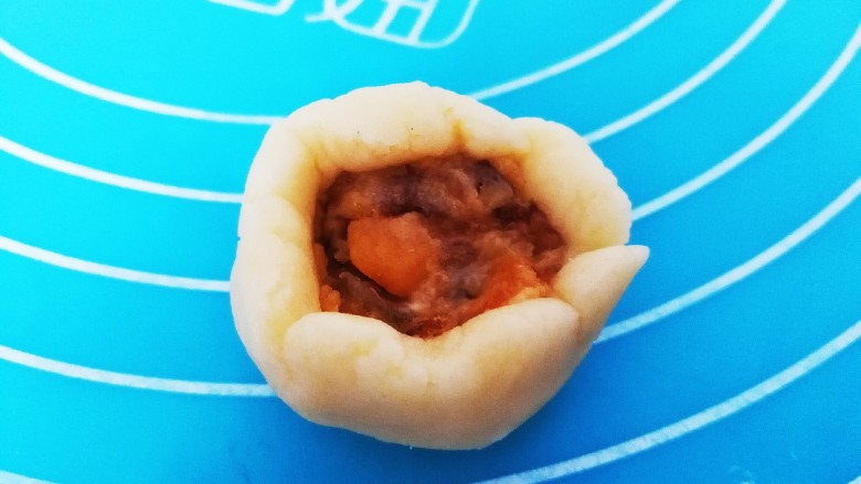 橙味肉松一口酥,取一份面团,上面挖一点馅料,收口处捏紧,搓圆后压扁