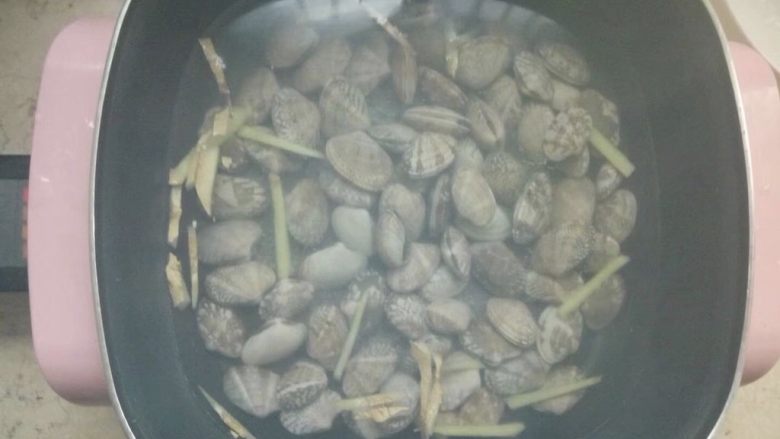 豆瓣酱炒花蛤,煮一锅水,放入姜丝和少量料酒,水开以后倒入浸泡过的花蛤煮。