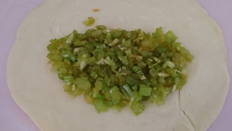 快手早餐&芹菜火腿手抓饼,把拌好的芹菜放到手抓饼上(如图)。