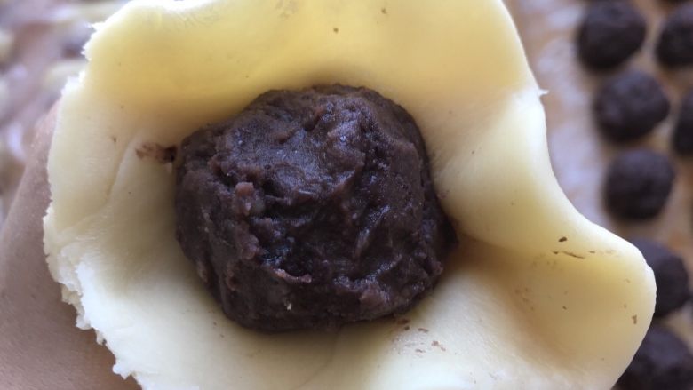 红豆蛋黄酥,然后收口,将收口捏紧,收口朝下放置。