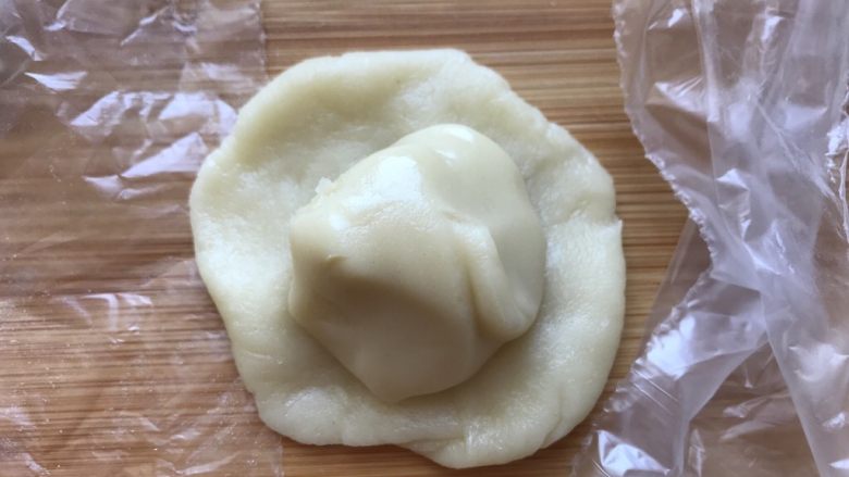 红豆蛋黄酥,用一个油皮小团包裹一个油酥面团,包好收口,将收口朝下放置。