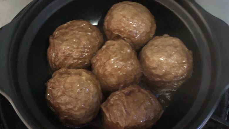 面筋包塞肉,砂锅烧热,放入面筋包,少放一点汤汁,盖上盖子开小火继续煮