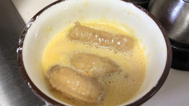 茶香鸡翅,腌制好的鸡翅放入蛋液中,蘸均匀后放入锅中煎炸。