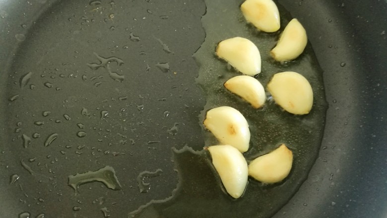 干锅牛蛙,锅中加一些底油,放入大蒜煸炒至焦黄。