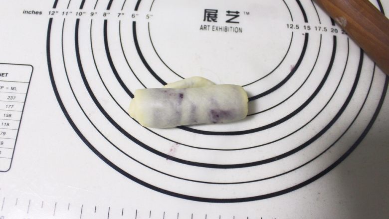 旋风紫薯油酥烧饼,取包好的剂子,用擀面杖擀成牛舌状之后,从下往上卷起来