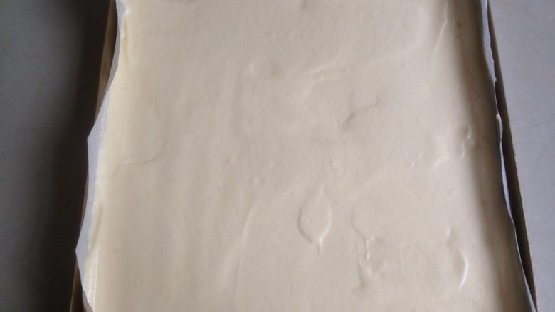 草莓层叠蛋糕,拌好的蛋糕糊从烤盘上方高一点的位置倒下来,用刮板刮平表面。烤盘里面提前铺上油纸。