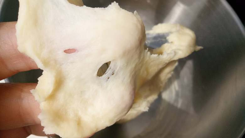 千层汉堡,把汤种和主面团除<a style='color:red;display:inline-block;' href='/shicai/ 887'>黄油</a>以外的其他材料一起放入厨师机里揉10分钟左右，能拉出这样的膜。这时放入<a style='color:red;display:inline-block;' href='/shicai/ 887'>黄油</a>继续揉。 
