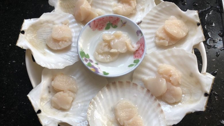 粉丝蒸扇贝,总刀把扇贝破开,沿着壳壁小心的取下贝肉,去掉内脏和腮,留下壳肉和月牙形的黄(我们家不喜欢,我全给扔掉了),把贝肉分到贝壳上。