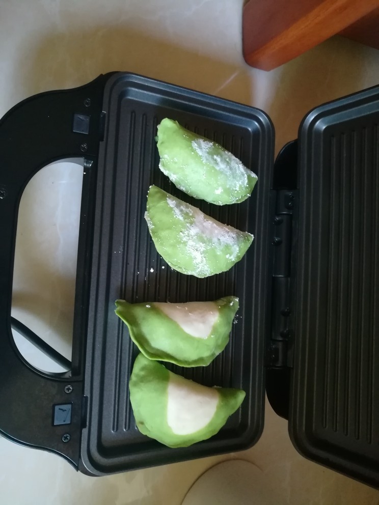 好看更好吃的翡翠白菜煎饺,电饼铛预热,整齐摆好翡翠白菜饺子,盖上盖子。