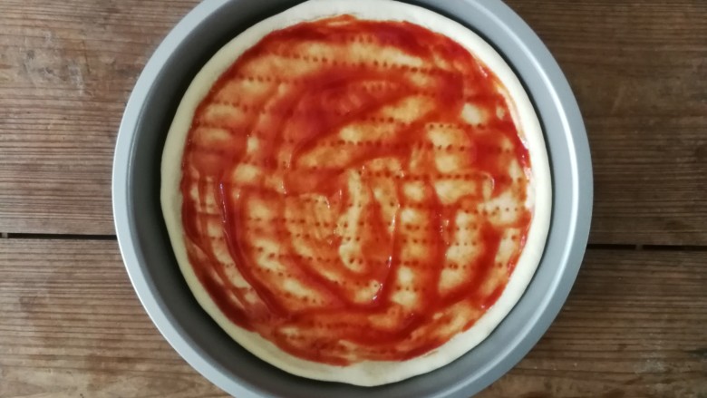 薄底香肠披萨,烘烤5分钟后的披萨底取出,用勺子涂抹一层<a style='color:red;display:inline-block;' href='/shicai/ 699'>番茄酱</a>