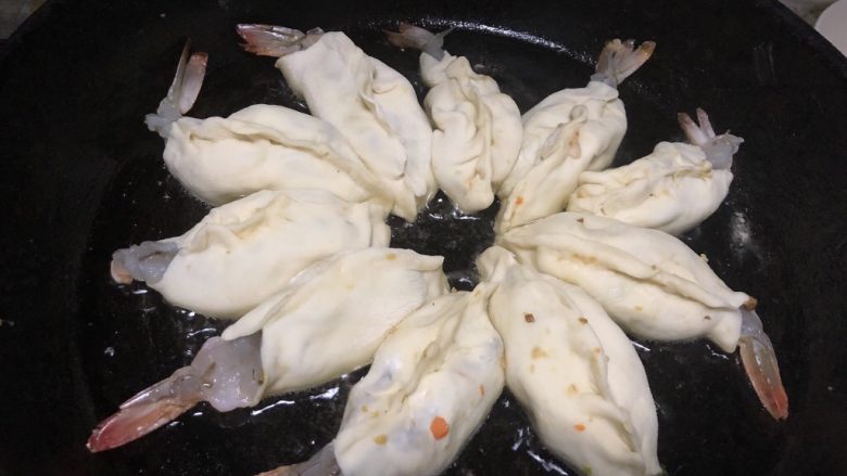美味虾蛋报饺,平底锅中放入油,烧热之后,将虾饺整齐摆好,大火煎2分钟之后转入小火,并且倒入小半碗水,然后盖上锅盖小火焖8分钟
