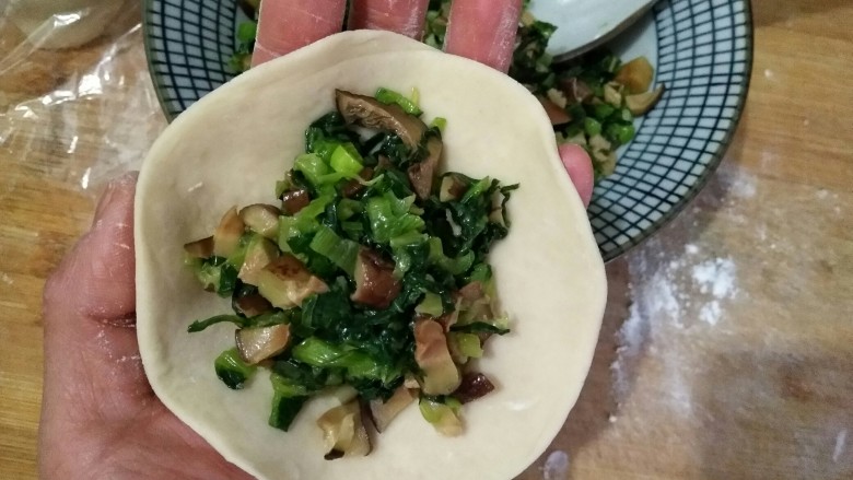 香菇油菜包,将面剂擀成中间后边缘薄的面皮,在中间填入适量的馅料。