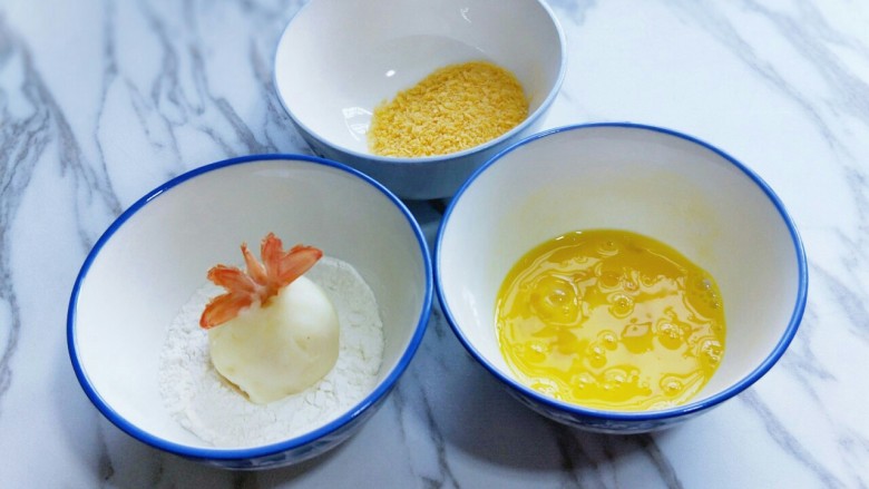 #辅食计划#黄金凤尾虾#煮蛋器版#,首先将包好土豆泥的红虾放入面粉器具中,均匀沾满面粉。