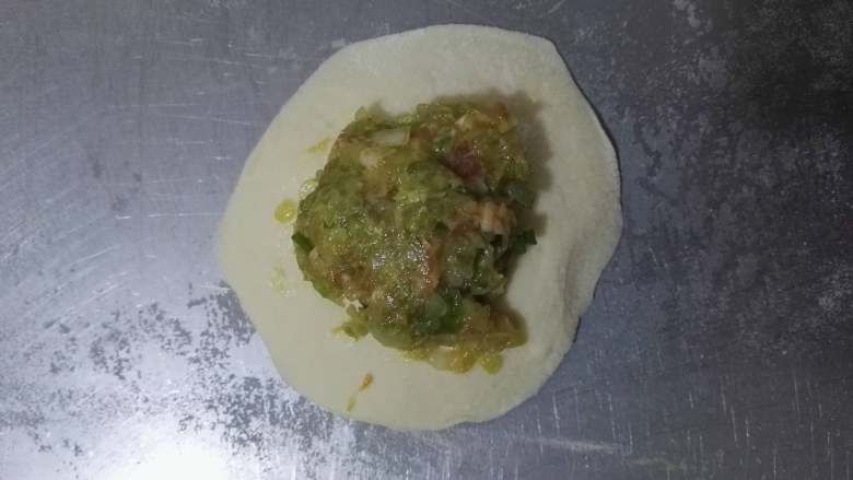 亦饭亦菜+美味+猪肉白菜包,将适量的猪肉白菜馅放在包子皮上,然后用提褶的方法将包子捏好、捏紧。