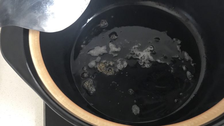 红烧猪蹄,用铲子把冰糖拍碎,冰糖加热很容易拍碎,等冰糖化开变成焦糖色。冰糖一定不要炒糊了,颜色不用太深就快速放入猪蹄翻炒。