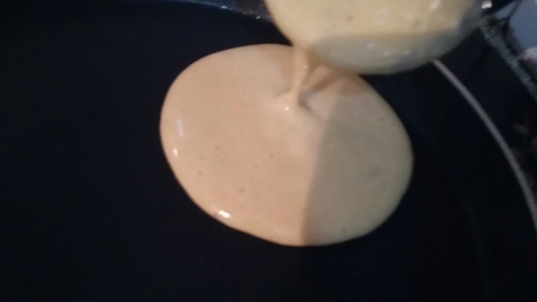 鲜香美味的香蕉松饼,用勺子挖一勺面糊,放入锅中,面糊会自动流动成圆形。