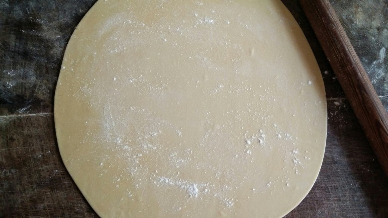 手擀面,在面饼表面撒些薄面,用擀面杖慢慢擀开。