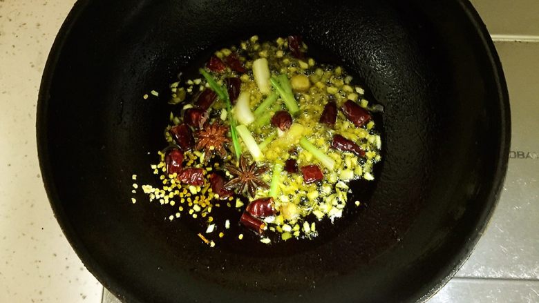 梅菜扣肉,锅中放入50ml食用油,待油五成热时放入姜片,蒜末,小葱白段,2颗八角,干辣椒剪成段放入锅中炒出香味。