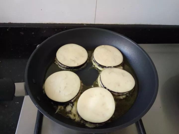 茄子肉饼,煎锅中放入油，中小火，放入茄盒煎。